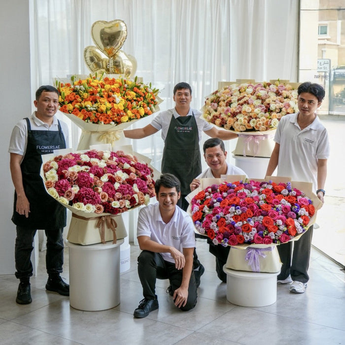Flowers.ae florist team with luxury oversized rose bouquets in mixed colours and gold heart balloons in Dubai studio